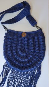 Navy blue crocheted crossbody purse with fringe.